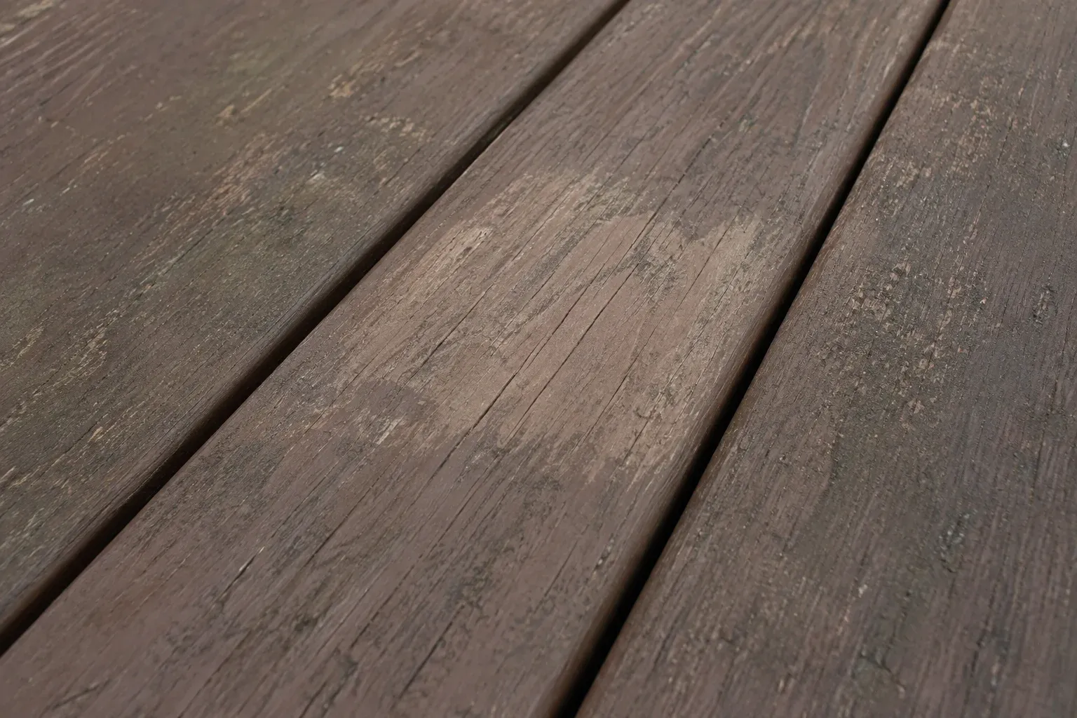 Small cleaned test area showing remaining stain wear on dry deck boards.